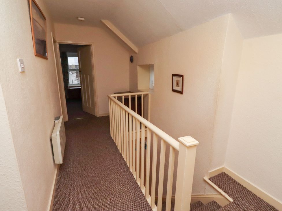 A hallway with staircase and doorways at Wayside Cottage in Newton-by-the-Sea