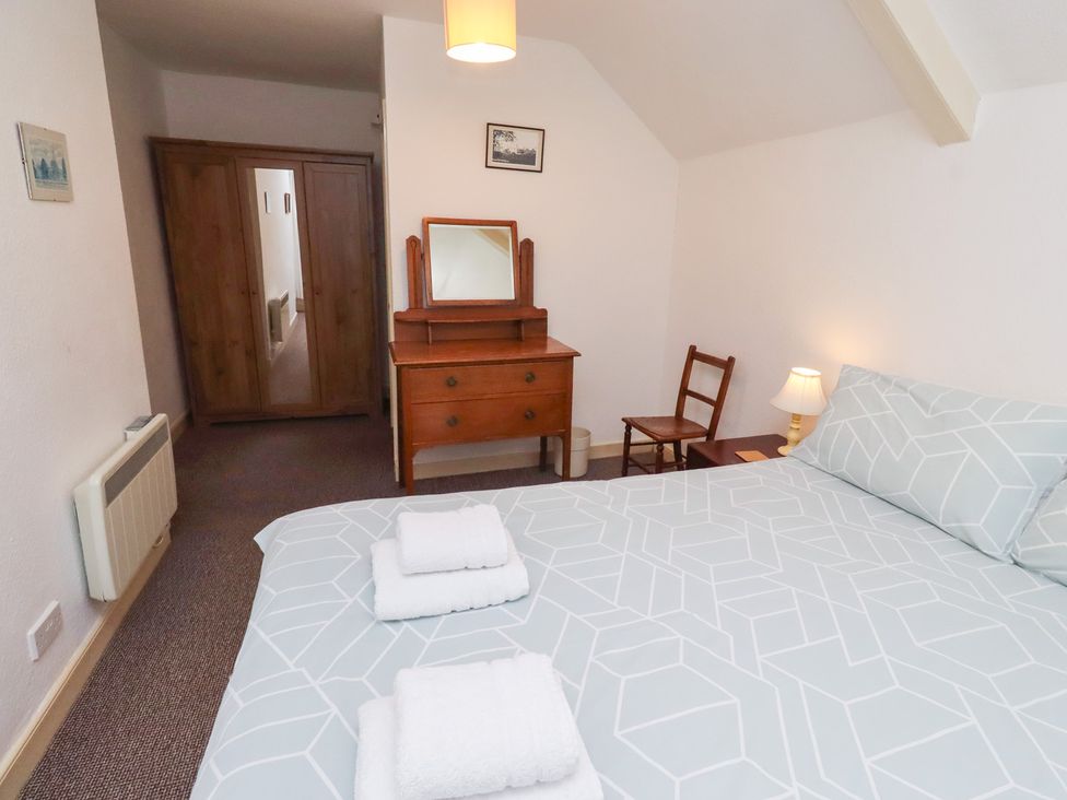 A bedroom with a bed, dresser, and chair at Wayside Cottage in Newton-by-the-Sea