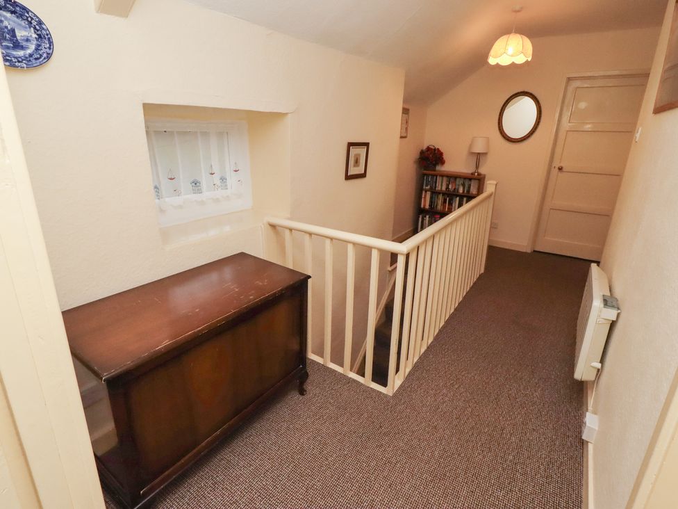 A hallway with a table and bookshelf at Wayside Cottage Newton-by-the-Sea
