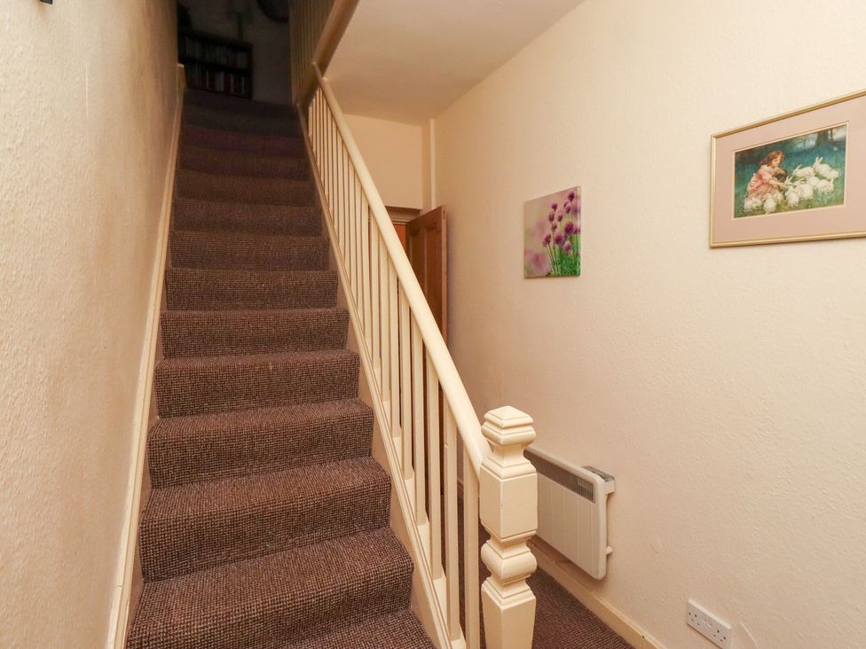 A staircase with a railing and wall art at Wayside Cottage in Newton-by-the-Sea