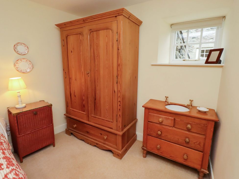 A bedroom with a wooden armoire and vanity at Wynding Down in Bamburgh