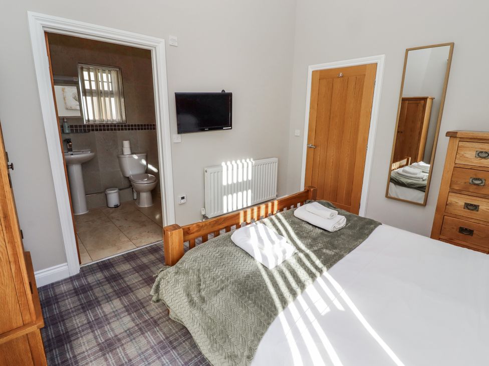 A bedroom featuring a bed, television, and door to bathroom at Red Fox in Lucker