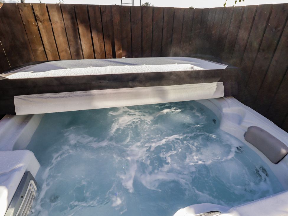 A hot tub with water and cover in an outdoor area at Red Fox in Lucker