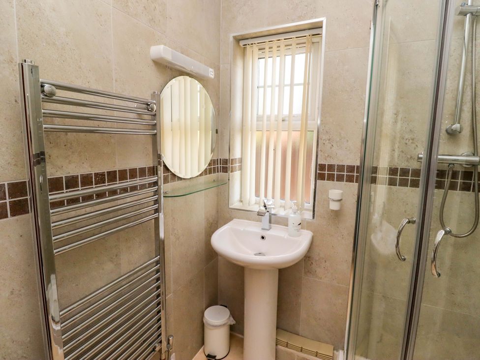 A bathroom with a shower, wash basin, and towel radiator at Roe Deer in Lucker
