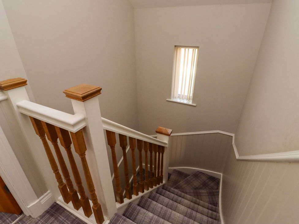 A staircase with wooden railing and window at Roe Deer in Lucker