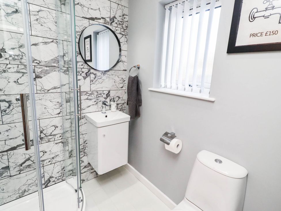A bathroom with a shower, sink, and toilet at Flora Cottage Beadnell