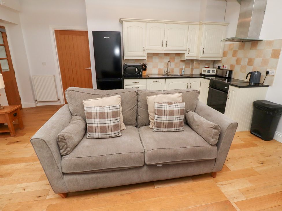 A living room with a sofa and kitchen area at Chiff Chaff in Lucker