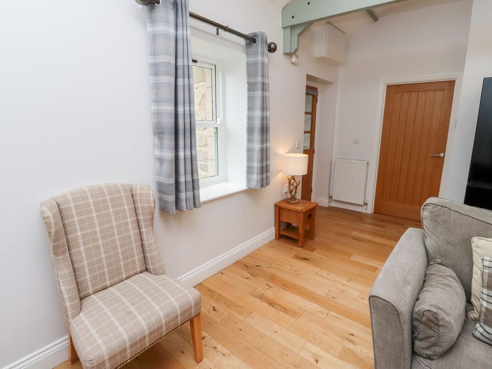 A living room with curtains, a chair, a lamp and a sofa at Chiff Chaff in Lucker