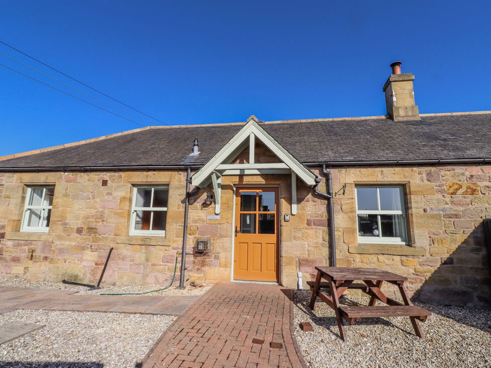 An outdoor view of a stone cottage with a brown door at Greenfinch in Lucker