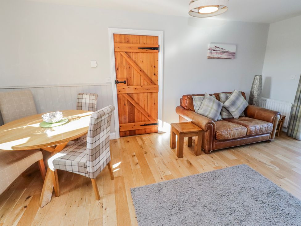 A living room with a sofa and dining table at Greenfinch in Lucker