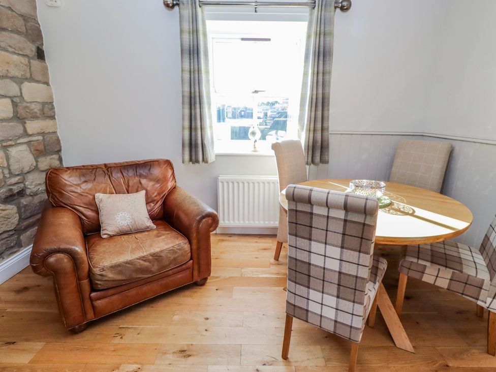 A dining room with a table and leather chair at Greenfinch in Lucker