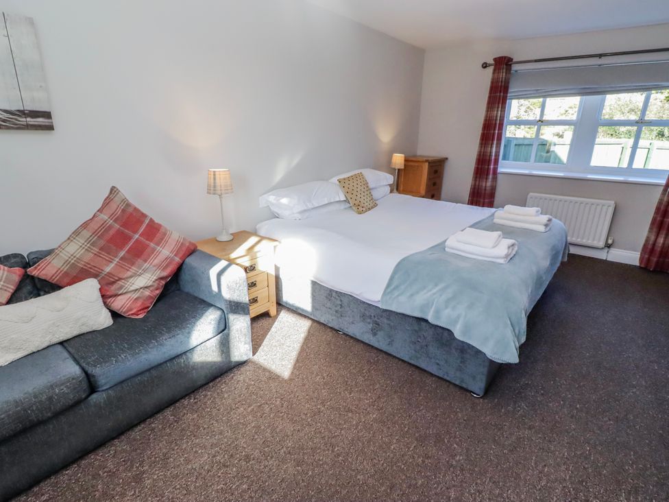 A bedroom with a bed and a sofa at Greenfinch in Lucker