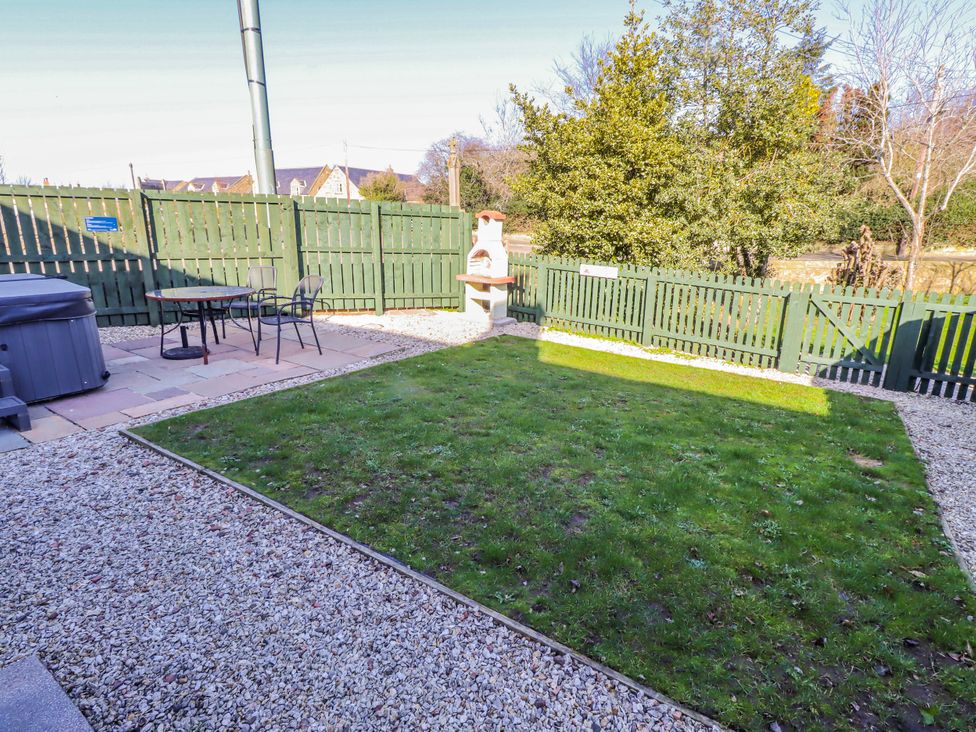 A garden with a hot tub and table with chairs at Greenfinch in Lucker