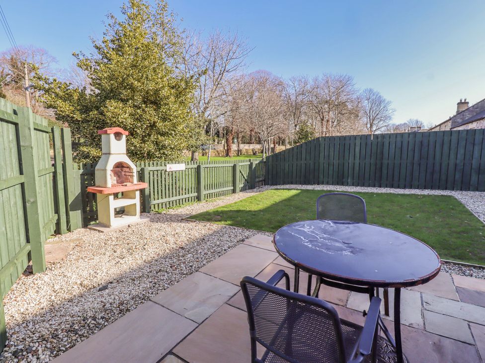 A garden with a table and chairs next to a grill at Greenfinch in Lucker