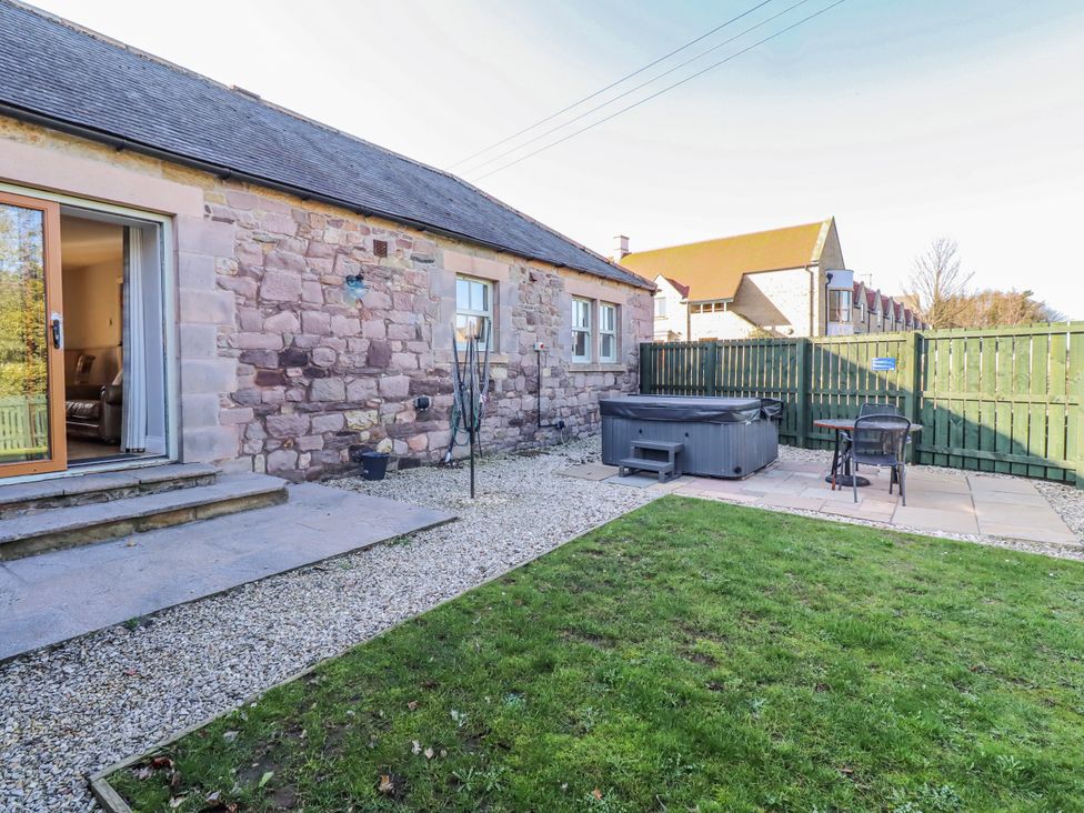 A garden with a hot tub and chairs at Greenfinch in Lucker