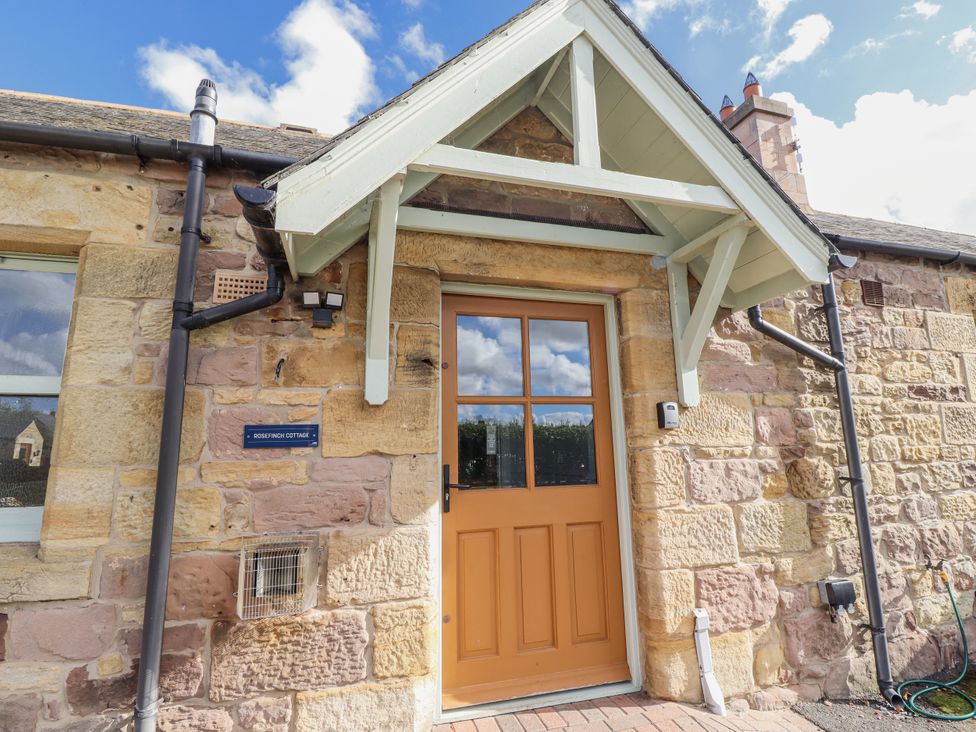 An entrance with a front door and stone wall at Rosefinch in Lucker