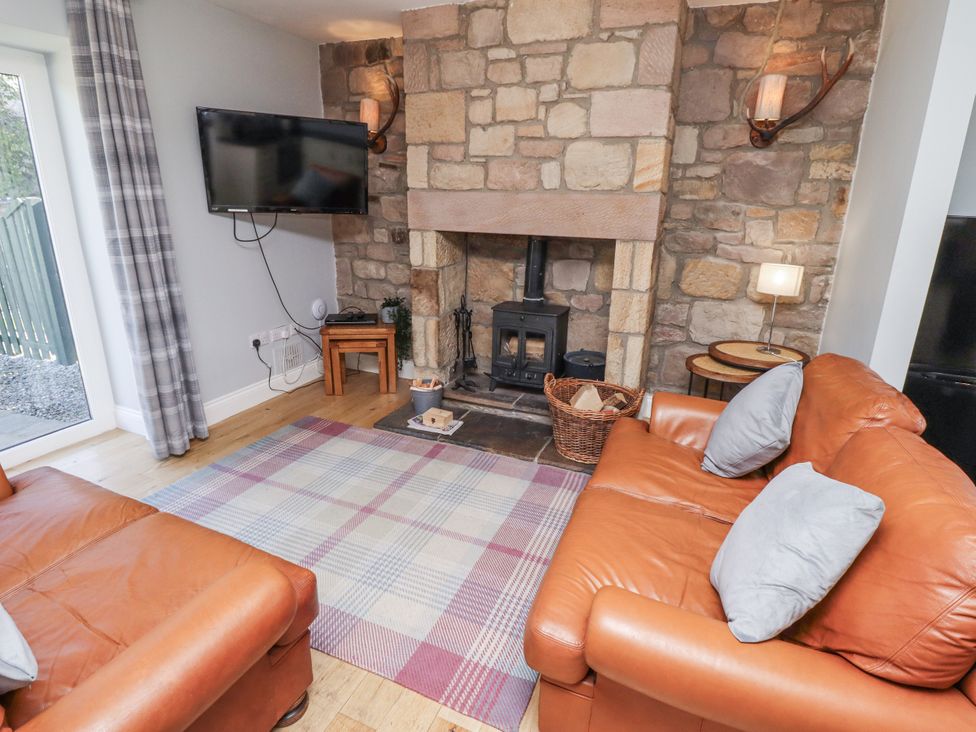 A living room with a fireplace and sofa at Rosefinch in Lucker