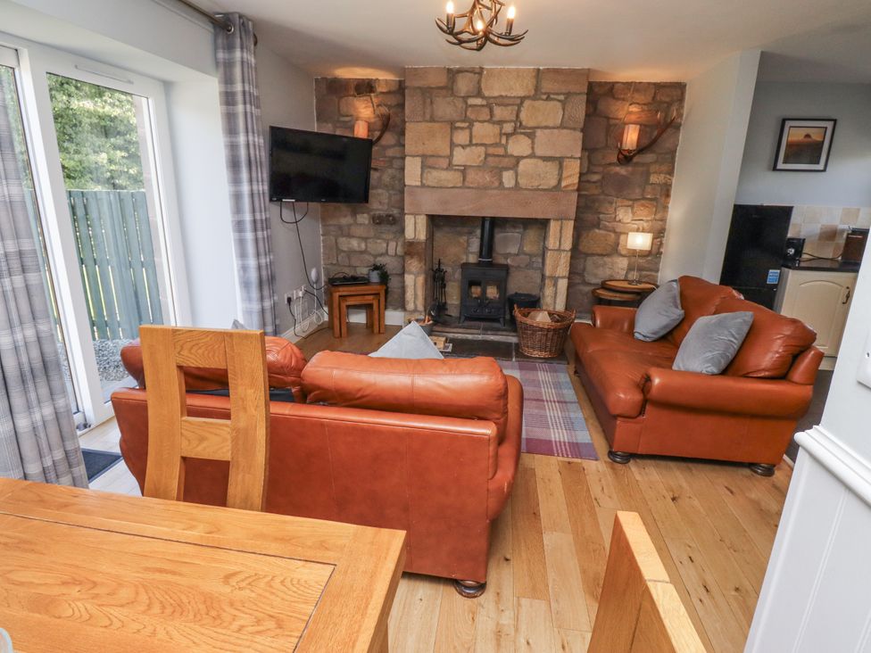 A living room with a fireplace and sofas at Rosefinch in Lucker