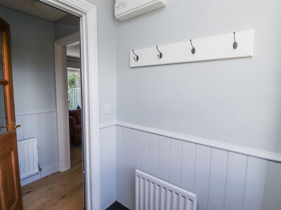 A hallway with wall hooks and radiator at Rosefinch in Lucker