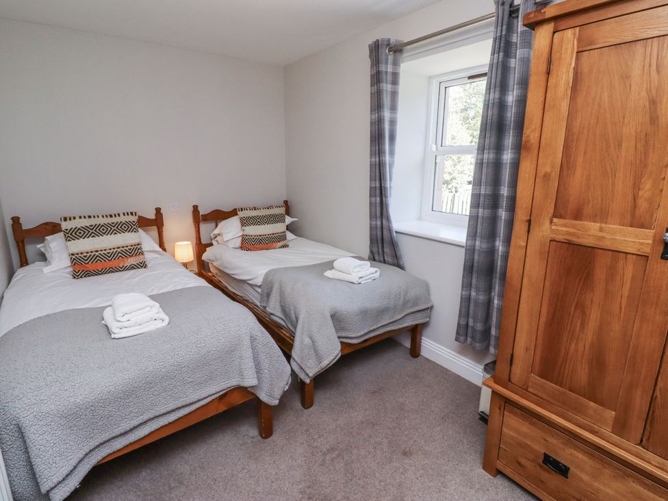 A bedroom with two beds and a wardrobe at Rosefinch in Lucker