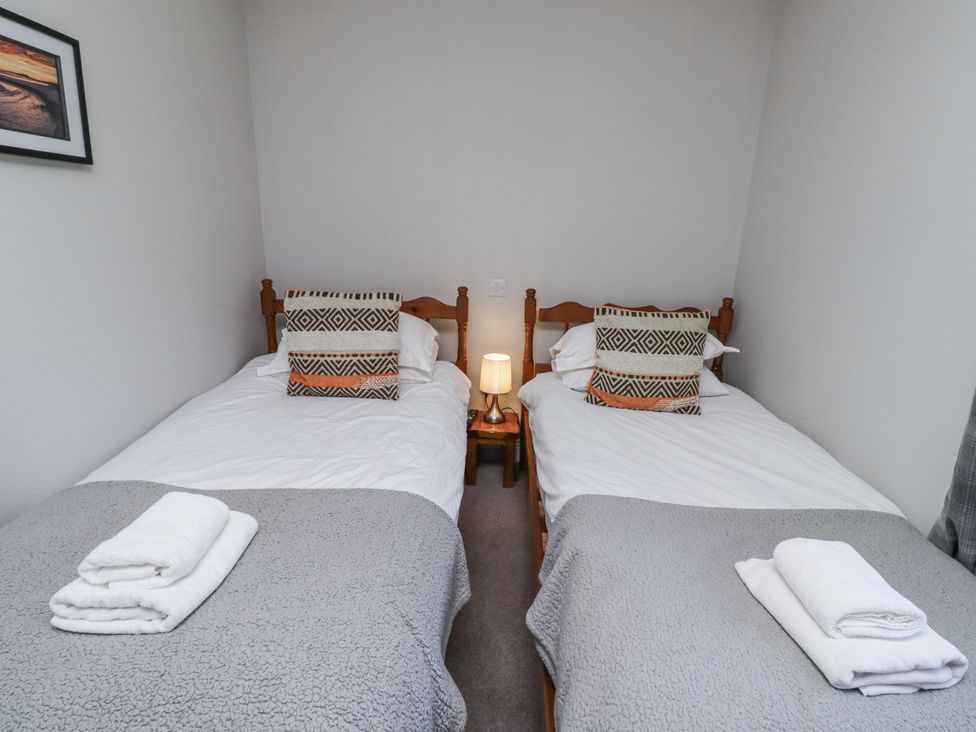 A bedroom with two single beds and a lamp at Rosefinch in Lucker