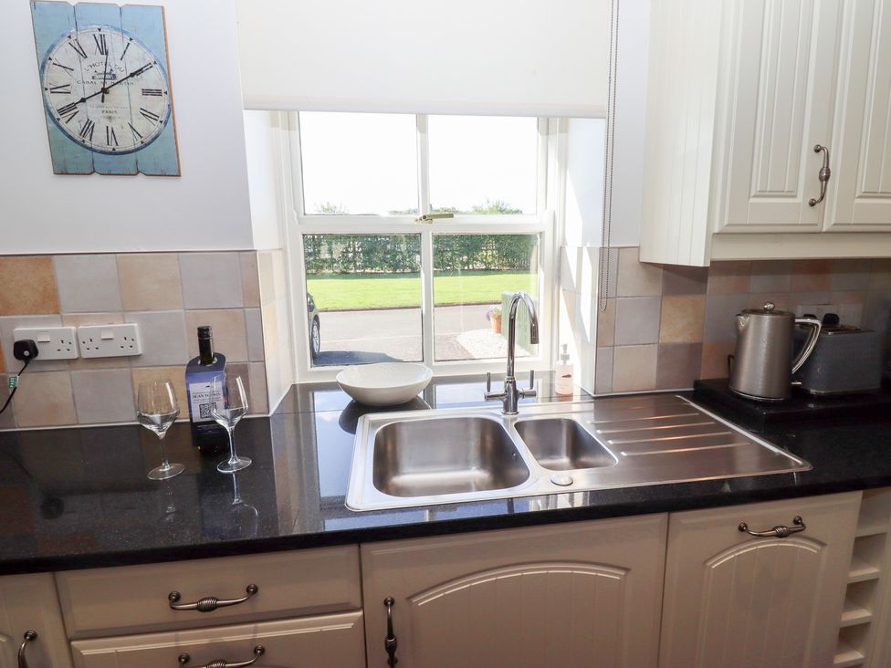 A kitchen with a sink and wine glasses at Chaffinch in Lucker