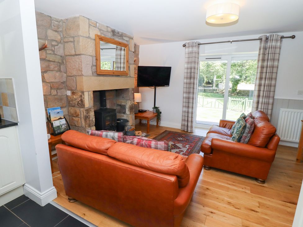 A living room with a fireplace and sofa at Chaffinch in Lucker