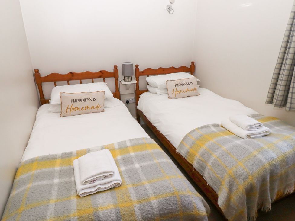 A bedroom with two beds and a bedside table at Chaffinch in Lucker