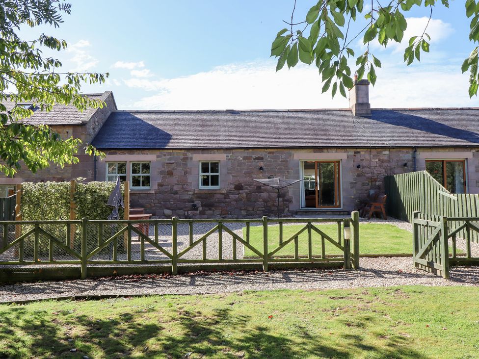 An outdoor area with a stone building and a wooden fence at Chaffinch in Lucker