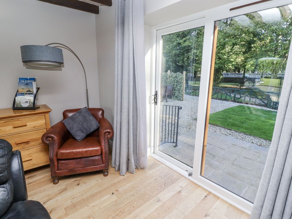A living room with an armchair and sliding doors at Goldfinch in Lucker