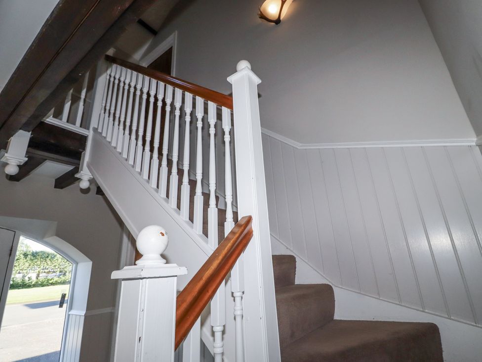 A staircase with a handrail and light fixture at Goldfinch in Lucker