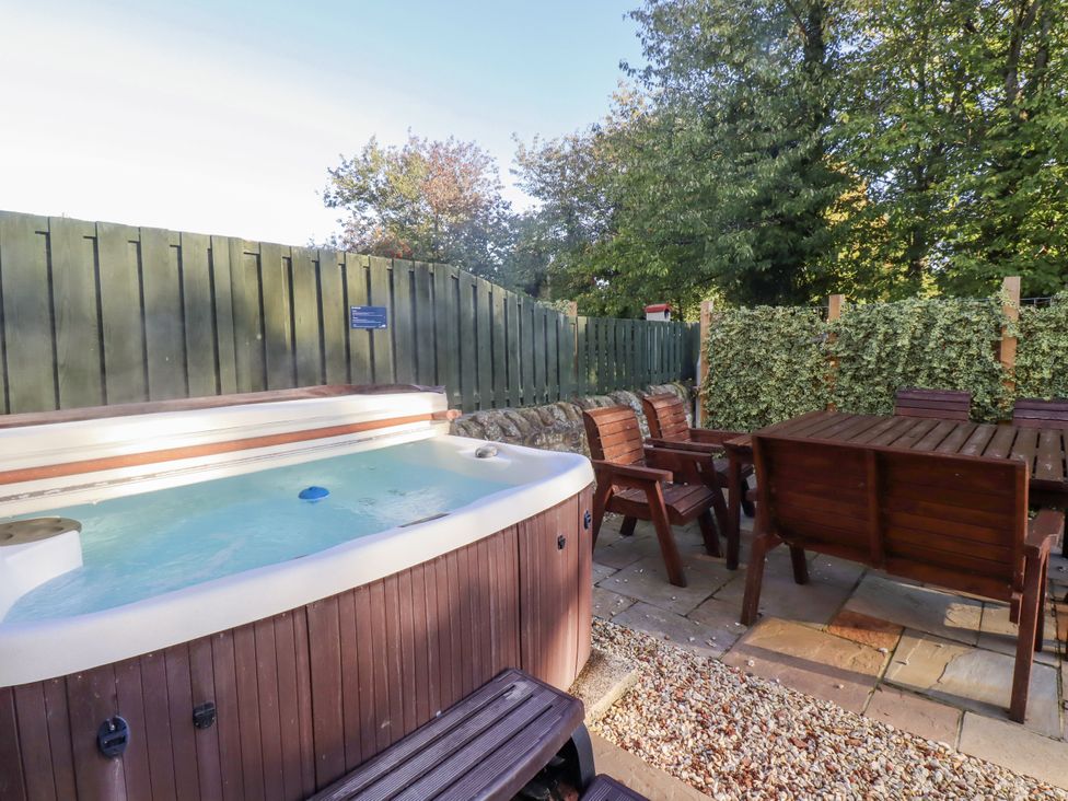 An outdoor area with a hot tub and wooden furniture at Goldfinch in Lucker