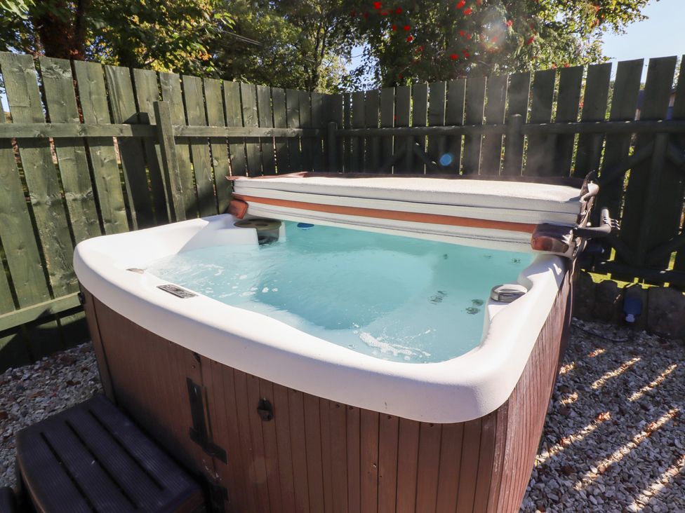 A hot tub in a fenced outdoor area at Bullfinch in Lucker