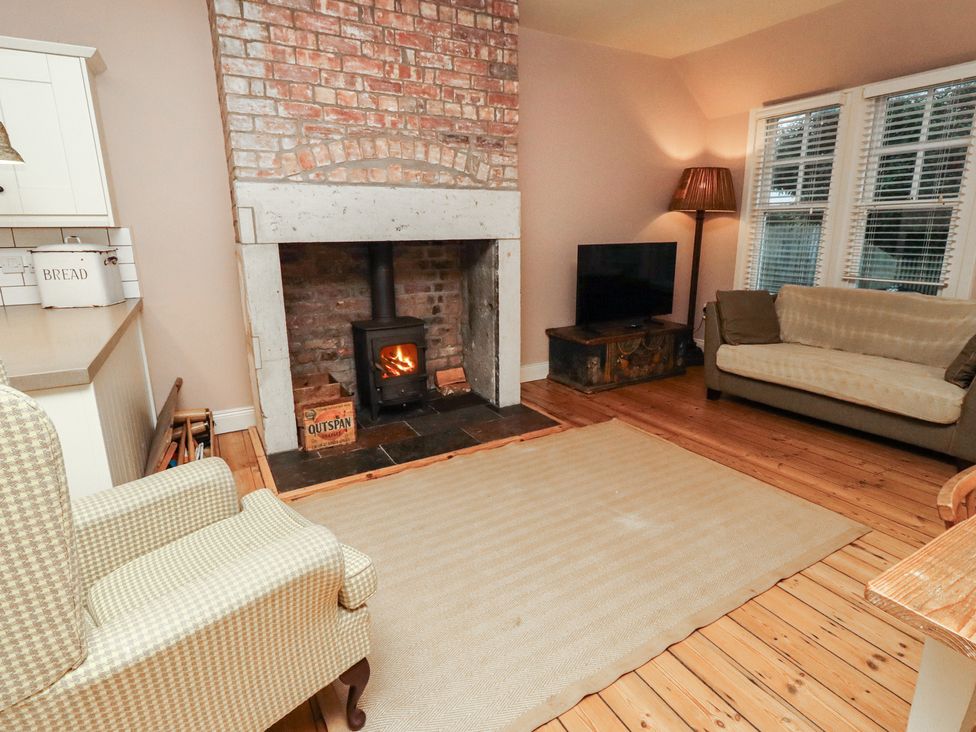 A living room with a fireplace and a sofa at Armstrong Cottages No6 in Bamburgh