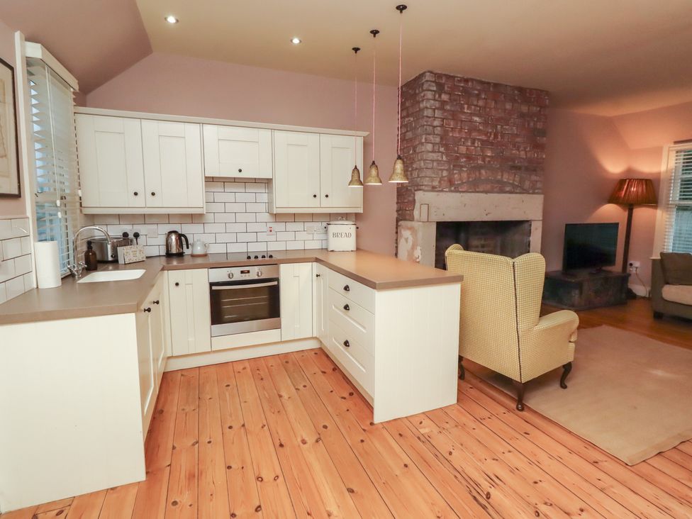 A kitchen with cabinets, sink, and stove at Armstrong Cottages No6 in Bamburgh