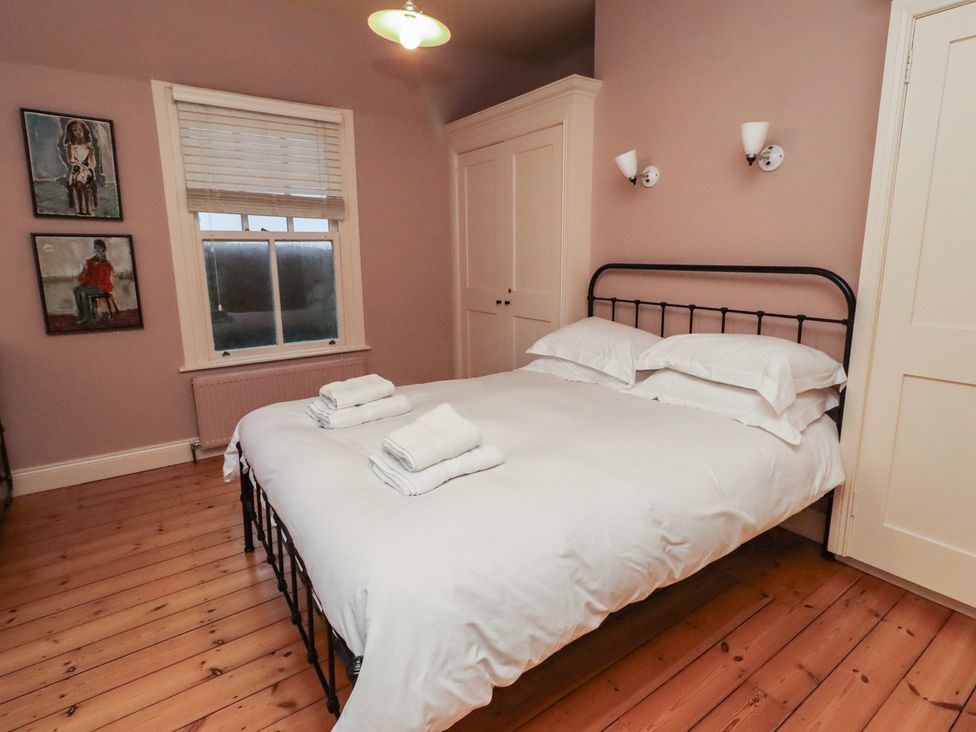 A bedroom with a bed and artworks on the wall at Armstrong Cottages No6 Bamburgh