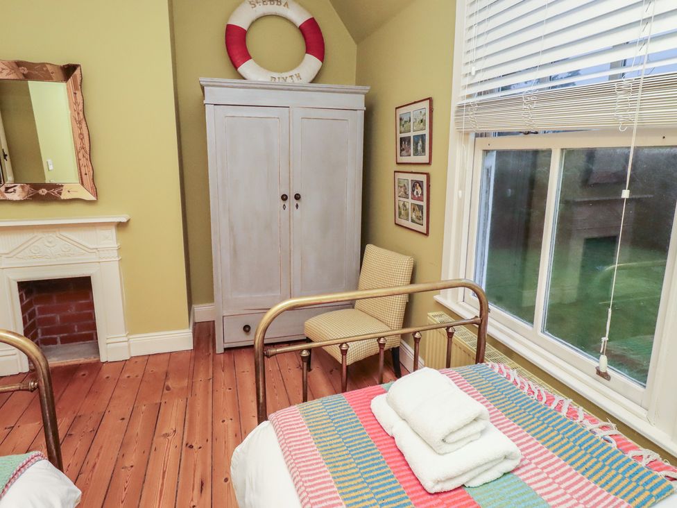 A bedroom with beds and a wardrobe at Armstrong Cottages No6, Bamburgh