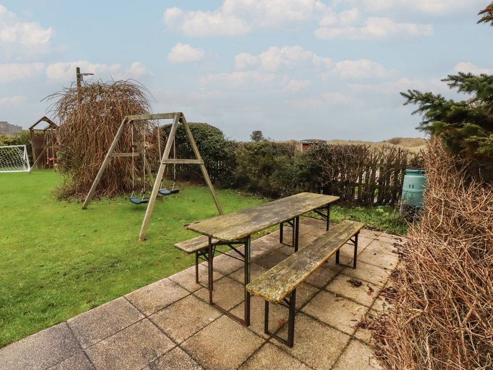 A garden with a table and swing set at Armstrong Cottages No6 in Bamburgh