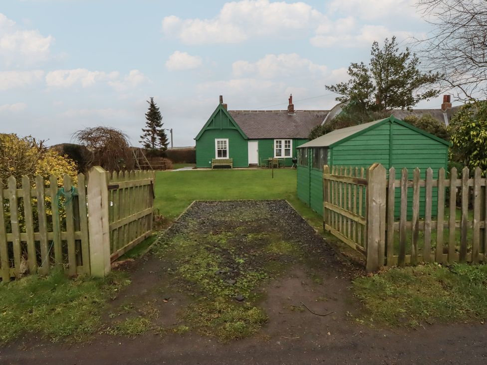 A garden with a green house and fence at Armstrong Cottages No6 in Bamburgh