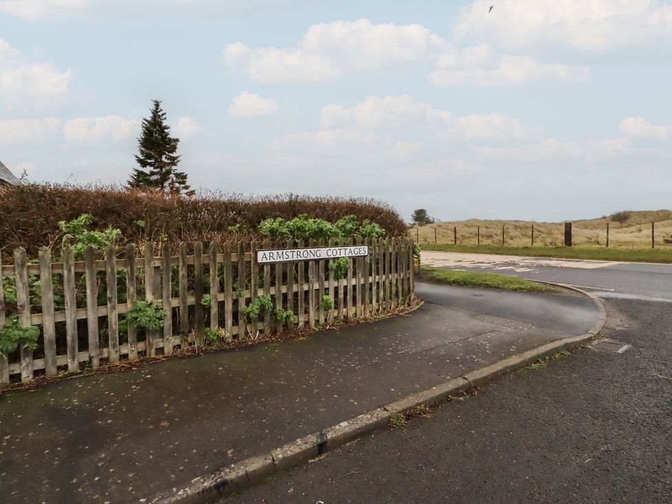 A sign indicating Armstrong Cottages at a road junction in Bamburgh