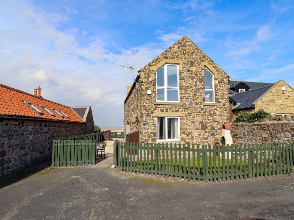 A house with a stone exterior and fenced yard at Pipistrelle in Bamburgh