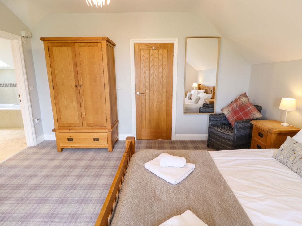 A bedroom with a wardrobe, bed, and mirror at Pipistrelle in Bamburgh