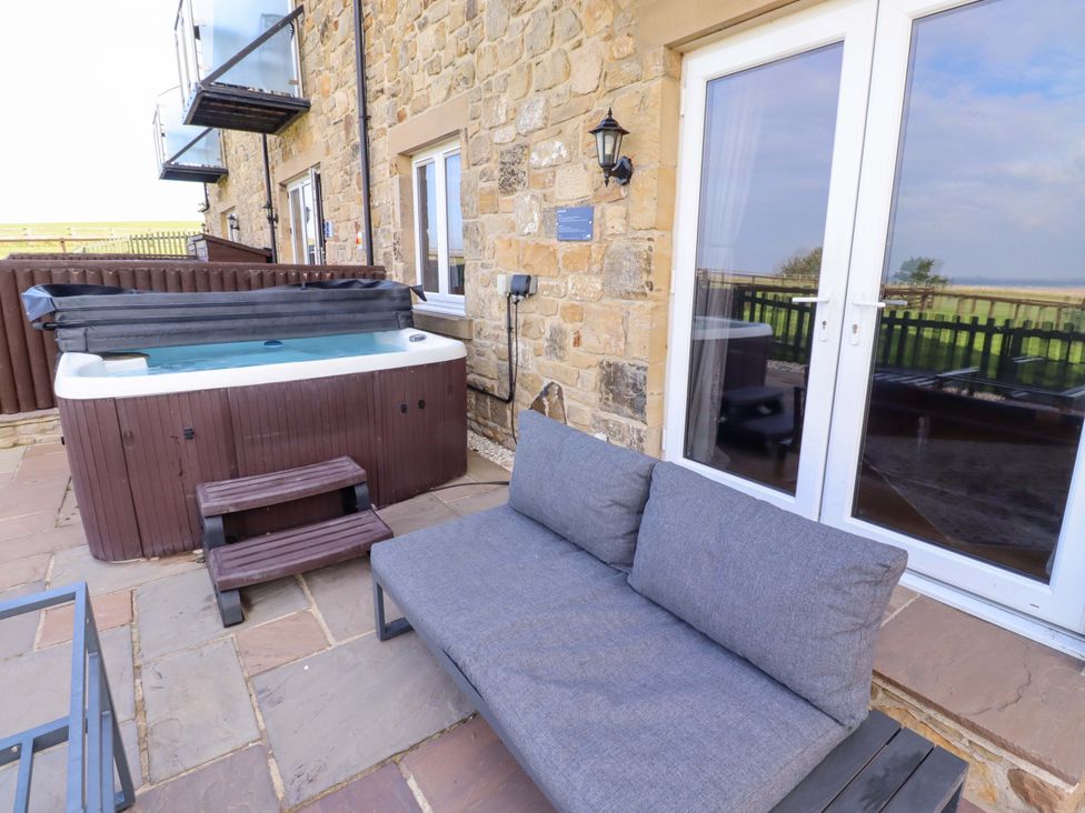 An outdoor space with a hot tub and sofa at Pipistrelle in Bamburgh