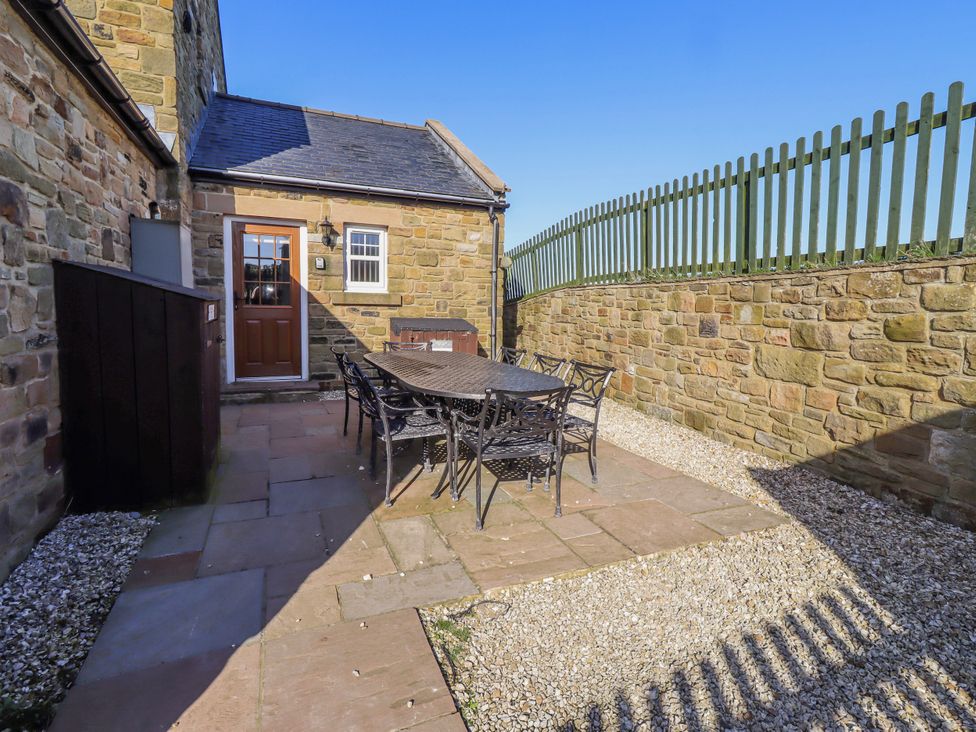 An outdoor seating area with a table and chairs at Goosander in Bamburgh