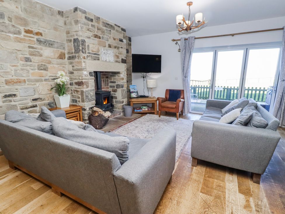 A living room with sofa and fireplace at Goosander in Bamburgh