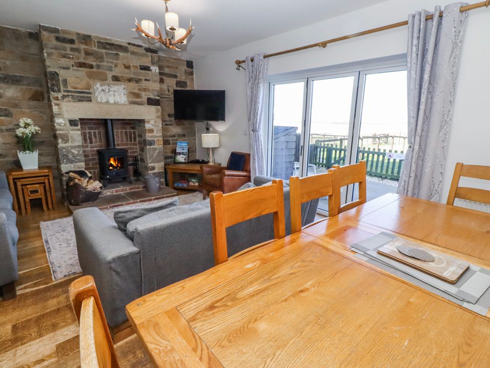 A living room with a fireplace and wooden table at Goosander in Bamburgh