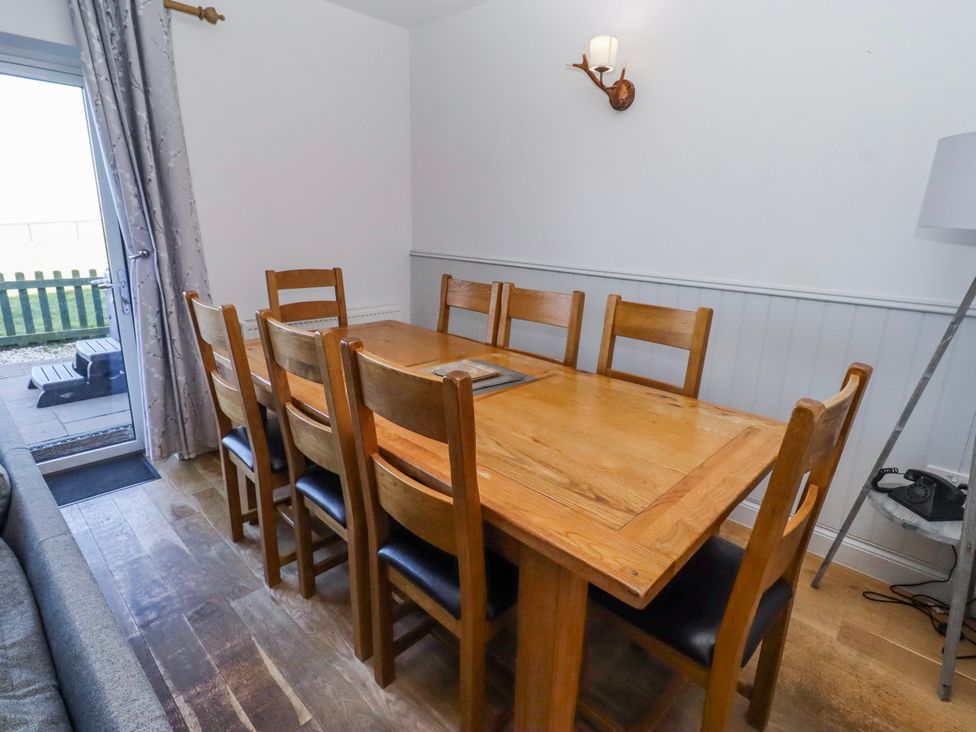 A dining room with a wooden table and chairs at Goosander in Bamburgh