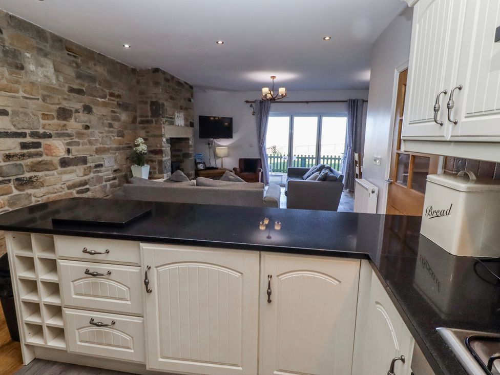 A kitchen with a view of the living area at Goosander in Bamburgh