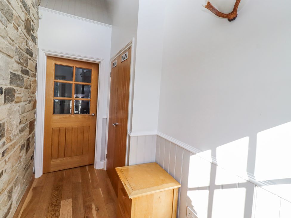 A hallway with a wooden door and box at Goosander in Bamburgh