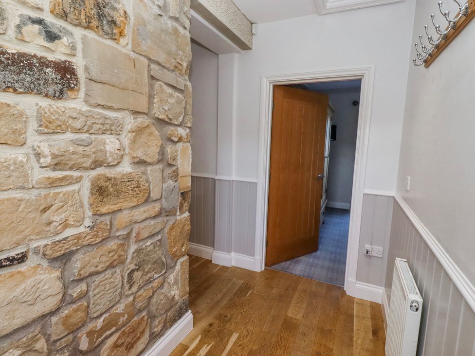 A hallway with a stone wall and a door at Goosander in Bamburgh